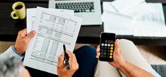 a person holding a calculator while looking at paperwork