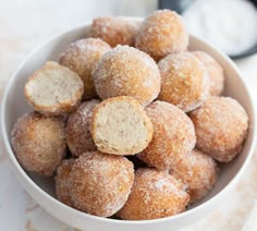 a white bowl filled with sugar covered donuts