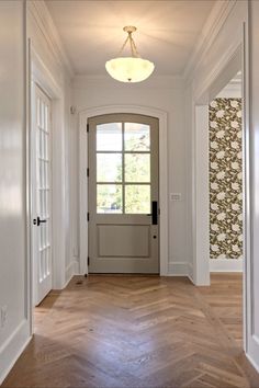 an empty hallway leading to a door with a light fixture on the ceiling above it