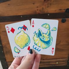 two playing cards are held up in front of a wooden box