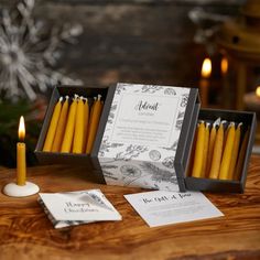 some yellow candles are sitting on a table next to cards and tags that read about