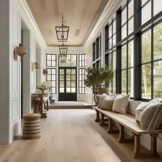 a long hallway with lots of windows and wooden benches on either side of the room