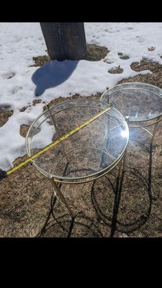 two glass tables sitting on top of snow covered ground