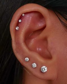 a woman's ear with three small diamond studs on the top of it