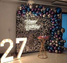 a birthday party with balloons and lights on the wall