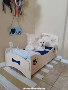 two white dogs laying in a wooden dog bed