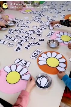 children are sitting at a table with numbers and flowers on them to make flower cards