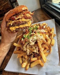 a person holding up a cheeseburger and french fries