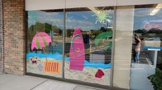 a store front window with an image of a beach scene and umbrellas painted on it