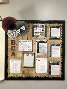 a bulletin board with some papers on it and a fan hanging from the wall next to it