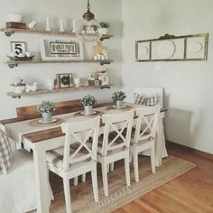 the dining room table is set with white chairs and place settings on shelves above it