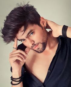 a man is posing with his hand on his head and looking at the camera while wearing a black shirt