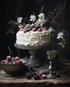 a cake with white frosting, berries and flowers on top is surrounded by other desserts