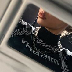 a close up of a person wearing a black and white shirt with a chain around their neck