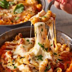 a person is taking a piece of pasta from a skillet