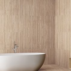 a white bath tub sitting on top of a wooden floor next to a wall mounted mirror