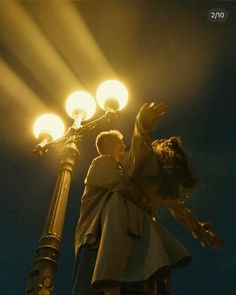 a man and woman standing on top of a street light