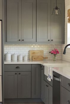 a kitchen with gray cabinets and white counter tops