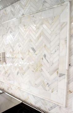 a kitchen with white cabinets and marble backsplash