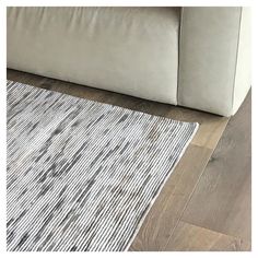 a white couch sitting on top of a wooden floor next to a gray and white rug