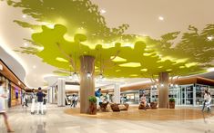 people are walking around in the lobby of a shopping mall with trees on the ceiling