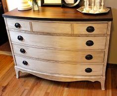 a white dresser with black knobs and drawers on it's sides, in front of a mirror