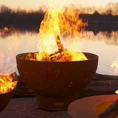 a fire pit sitting on top of a sandy beach next to a body of water