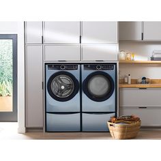 a washer and dryer sitting in a kitchen next to a basket on the floor