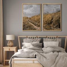 two paintings on the wall above a bed in a room with gray walls and wooden furniture