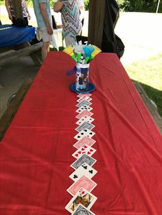 a red table cloth with playing cards on it and a can of drink sitting on top