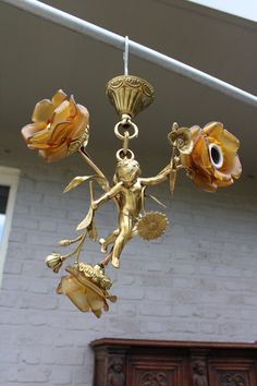 a chandelier hanging from the ceiling in front of a white brick building with flowers on it