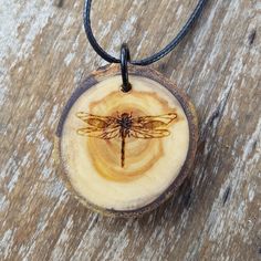 Show your love of nature with this natural tree slice pendant engraved with our original dragonfly design. In many cultures the Dragonfly is a symbol of adaptability and change. This is derived from the Dragonfly's ability to be at home in both water and air and its omnidirectional flight. *This wooden pendant is created with locally sourced wood and treated with mineral oil to preserve and hydrate the wood. *Comes with 20 inch waxed cord with a 2 inch chain extender for adjustable length. Dimen Wooden Pendant Necklace, Insect Necklace, Tree Slice, Dragonfly Design, Natural Tree, Tree Slices, Pendant Necklace Simple, Dragonflies Design, Key Hanger