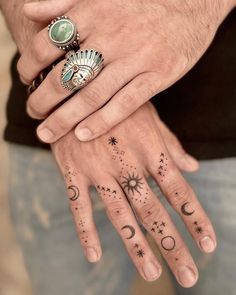 two people with tattoos on their hands and one holding the other's hand, both wearing rings