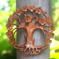 a metal tree with flowers on it's face is hanging from a wooden pole