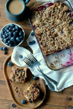 a blueberry crumbler pie and two cups of coffee on a wooden table