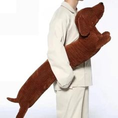 a man is holding a stuffed dog in his arms while wearing a sweater and pants