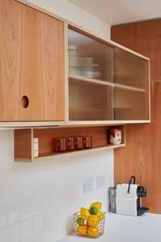 a kitchen with wooden cabinets and white counter tops, along with a basket of fruit