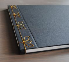 a black book with gold trim sitting on top of a wooden table