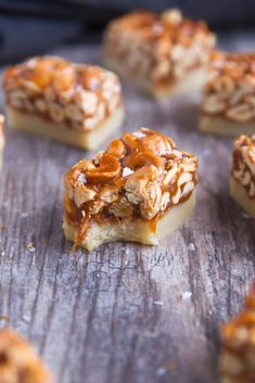 several pieces of dessert sitting on top of a wooden table with caramel toppings