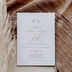 an elegant wedding card is laying on top of a furnishing blanket with the word sl written in cursive font