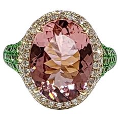 This luxurious 14k yellow gold ring boasts an enchanting 5.72 carat oval-cut tourmaline as its centerpiece, exuding a captivating blend of elegance and charm. The tourmaline is surrounded by a halo of sparkling diamonds, with a total diamond weight of 0.68 carats, adding brilliance and sophistication to the design. The band is adorned with 0.66 carats of rich green garnets, further enhancing the ring’s vibrant and eye-catching aesthetic. The combination of the pink-hued tourmaline, the sparkling diamonds, and the vivid green garnets creates a harmonious fusion of colors, making this ring an extraordinary statement piece. Perfect for special occasions or as a unique addition to a fine jewelry collection, this ring showcases impeccable craftsmanship and timeless beauty. 14 Karat Yellow Gold Garnet And Diamond Ring, Green Garnet, Fine Jewelry Collection, Sparkle Diamonds, Yellow Gold Rings, Cocktail Rings, Timeless Beauty, Tourmaline, Garnet