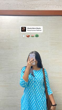 a woman taking a selfie in front of a wall with stickers on it