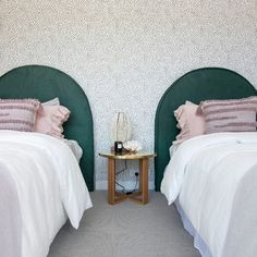 two twin beds with pink and white bedding in a room that has wallpaper