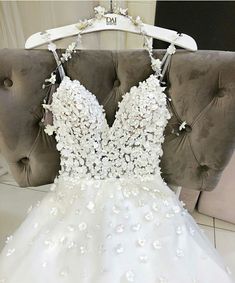 a white wedding dress with flowers on the front and back, sitting on a chair