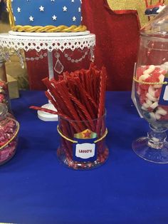 there are candy and candies in glass vases on the blue tablecloth at this party