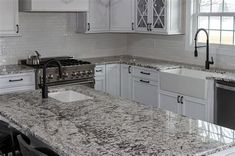 a kitchen with marble counter tops and white cabinets