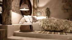 a bed with pillows and blankets on top of it next to a wall mounted mirror