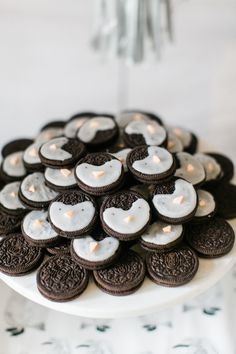 a white plate topped with lots of cookies and lit tea lights on top of a table