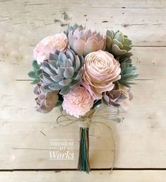 a bouquet of succulents and roses tied to a string on a wooden surface