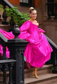 a woman in a pink dress is standing on some stairs